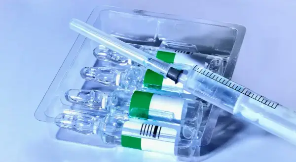 Zastrzyk po chemioterapii. Kilka ampułek leku w opakowaniu, obok leży strzykawka.