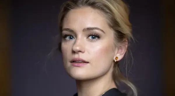 Alicia Agneson, med blå ögon och blont hår uppsatt i en hästsvans, bär en guldig örhänge.