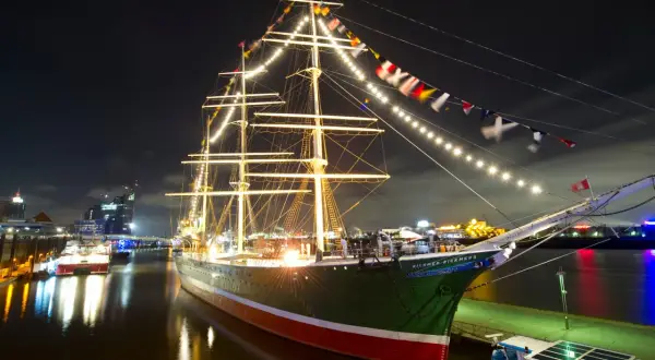Großes Segelschiff mit Lichterketten und Flaggen im Hamburger Hafen bei Nacht, ein Highlight der museumsnacht hamburg.
