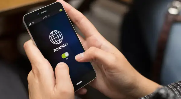 Dłoń włącza roaming na telefonie, przygotowując się do podróży po Czechach.
