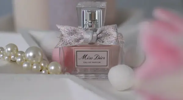 Elegancka butelka Miss Dior 100ml z kokardką, otoczona perłami i delikatnymi, białymi kulkami.