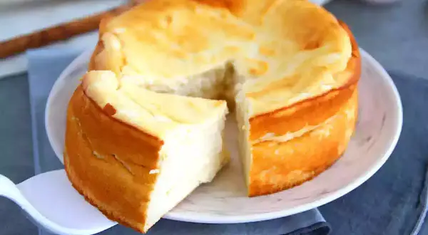 Gâteau au fromage blanc doré, une part coupée sur une assiette blanche.