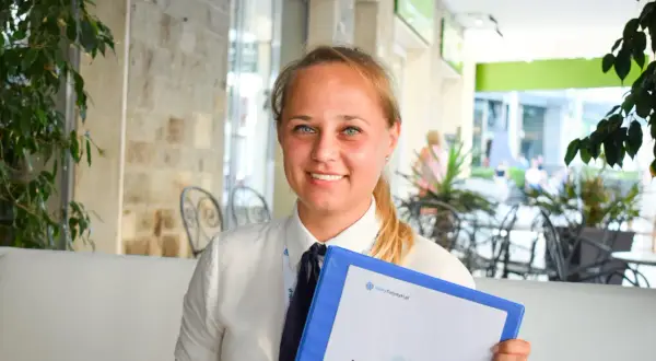 Uśmiechnięta rezydentka z niebieskimi oczami trzyma segregator z napisem "Informator".