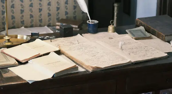 Bureau ancien avec des documents manuscrits, une plume, un encrier et un livre. Un aperçu de l'histoire familiale, peut-être des archives de geneafrance deces.
