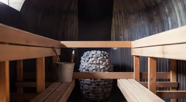 Drewniana sauna z kamiennym piecem. Czy sauna po treningu jest zdrowa? Odpoczynek i regeneracja po wysiłku.