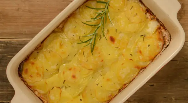 En gyllene pommes anna i en ugnsform, toppad med en rosmarinkvist. Perfekt till helgmiddagen.