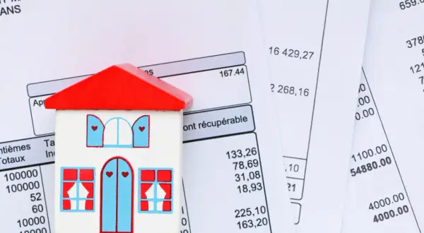 Maison en bois sur des factures. Apprenez comment calculer la taxe d'habitation.