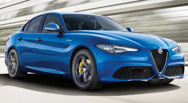 Błękitne Alfa Romeo Giulia Q4 Veloce w ruchu, z żółtymi zaciskami hamulcowymi i sportowym wyglądem.