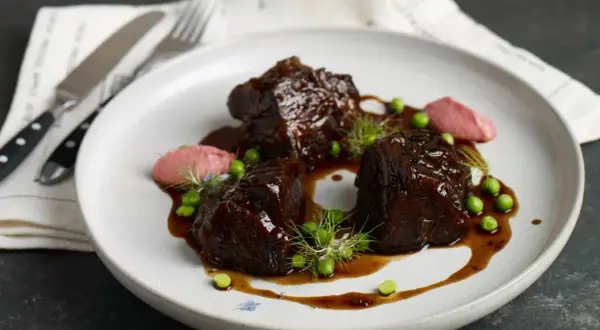 Pyszne policzki wołowe w sosie, podane z groszkiem i różowym purée. Idealny przepis na wykwintny obiad.