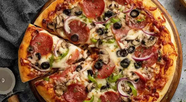 Pyszna pizza z pepperoni, oliwkami, pieczarkami i cebulą, idealna na szybki obiad. Ciasto na proszku do pieczenia sprawia, że jest puszyste i chrupiące.