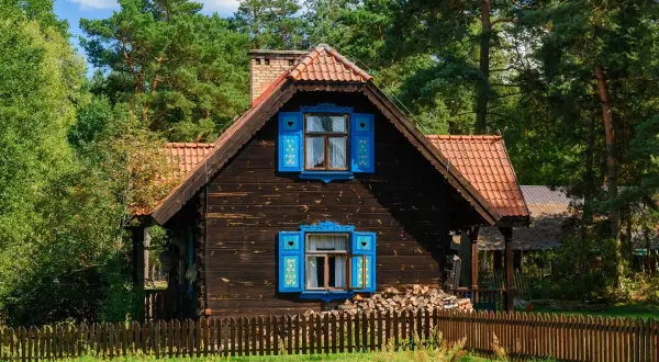 Drewniany domek z niebieskimi okiennicami, idealny na wypoczynek. Sprawdź, gdzie można wykorzystać bon turystyczny bez noclegu!