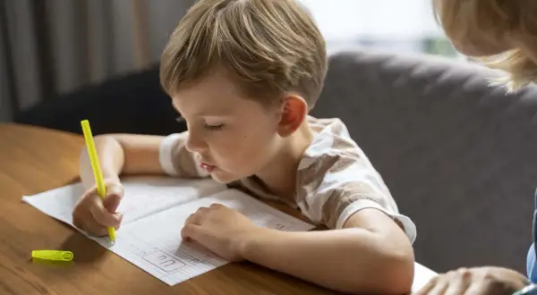 Niño concentrado practicando caligrafía en un cuaderno, un paso clave para como mejorar la letra de un niño.