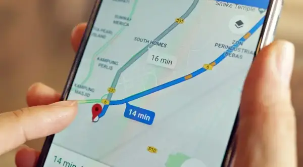 Palec dotyka ekranu smartfona z mapą, pokazując trasę i czas dojazdu. Dowiedz się, jak wysłać pinezkę, by udostępnić lokalizację.