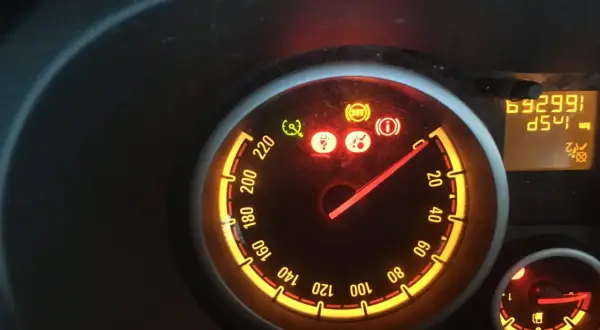 Tableau de bord allumé, voyant ceinture de sécurité rouge, ABS et information activés. Le compteur affiche 69299 km.