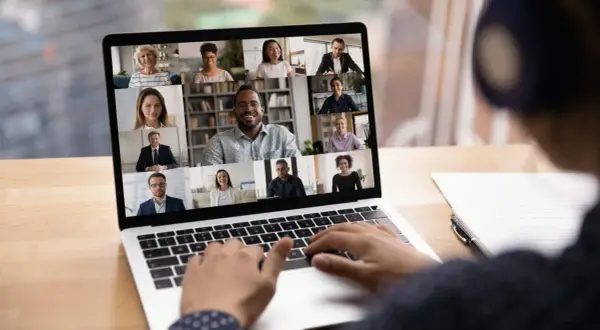 Schermo di un laptop con una videoconferenza in corso, mostrando volti sorridenti di persone che partecipano a eventi digitali.