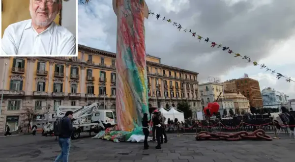 Ritratto di artista con inquadratura di una colorata statua di Pulcinella a Napoli, in piazza, con edifici storici sullo sfondo.