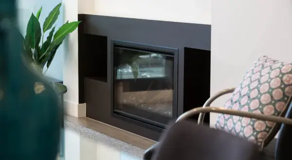 Moderner Kamin mit Glasfront und dekorativer Pflanze. Regelmäßiges Kehren ist wichtig, um die Sicherheit zu gewährleisten.