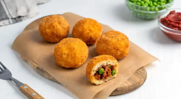 Arancini co to? Złociste kulki ryżowe, chrupiące na zewnątrz, z pysznym nadzieniem mięsnym i groszkiem w środku.