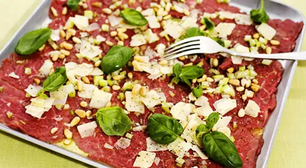 En läcker carpaccio med tunt skivat kött, pinjenötter, parmesan och basilika. Ett perfekt carpaccio recept för en förrätt.