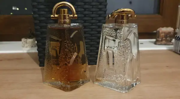 Dwie butelki Givenchy Pi: jedna pełna bursztynowego płynu, druga pusta, obie z ozdobnymi złotymi nakrętkami.