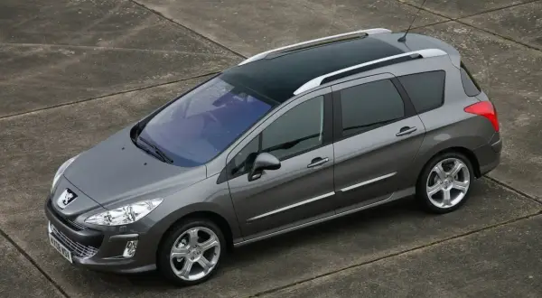 Szary Peugeot 308 SW z 2011 roku z panoramicznym dachem, zaparkowany na betonowej nawierzchni.