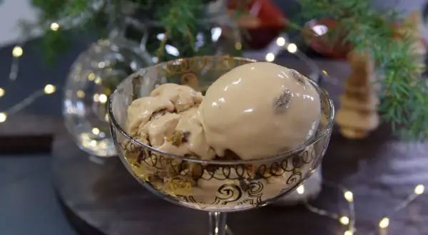 En skål med krämig kokosglass, perfekt för ett hemmagjort kokosglass recept. Julbelysning och gran i bakgrunden.