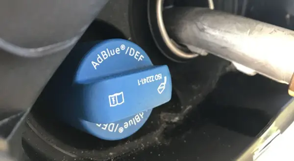 Niebieski korek wlewu AdBlue z napisem "AdBlue®/DEF" i symbolem ostrzegawczym. Sprawdź, ile adblue zostało.