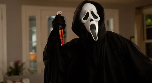 Postać w masce Ghostface z nożem, ikona najlepszych slasherów, czeka w mroku.