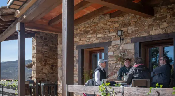 Gente disfrutando en la terraza de uno de los restaurantes de Horcajuelo de la Sierra, con vistas a la montaña.