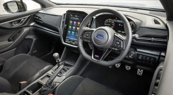 Wnętrze Subaru STI z dużym ekranem dotykowym, cyfrowymi zegarami i sportową kierownicą. Gotowy na jazdę!