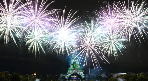 Spectaculaire feu d'artifice parisien illuminant la Tour Eiffel de mille feux. Des gerbes de lumière blanche et violette explosent dans le ciel nocturne.