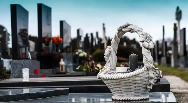 Kamienna ozdoba na nagrobku, symboliczny wiersz dla zmarłej mamy. W tle cmentarz, nagrobki i znicze.