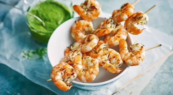 Gebratene Riesengarnelen auf Spießen, serviert mit einer grünen Sauce. Ein köstlicher Appetizer, der Lust auf mehr macht.