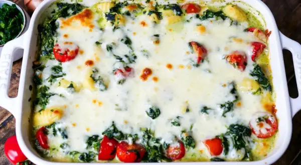 Gnocchi Spinat Auflauf mit geschmolzenem Käse und Kirschtomaten, ein köstliches Gericht, das zum Genießen einlädt.