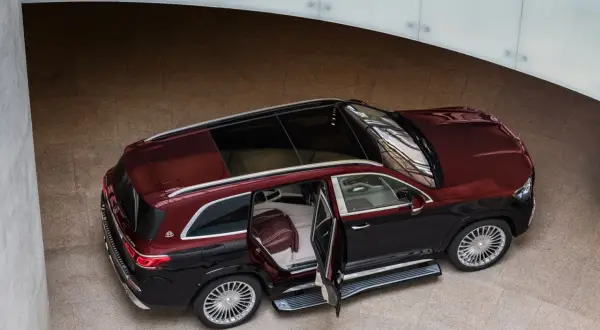 Elegancki, dwukolorowy Maybach GLS 600 z otwartymi drzwiami, prezentujący luksusowe wnętrze.