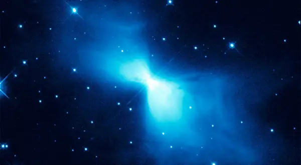 En lysande blå nebulosa, likt en fjäril, lyser upp den mörka rymden. Stjärnor glittrar runt den, en påminnelse om den extrema temperatur rymden kan ha.