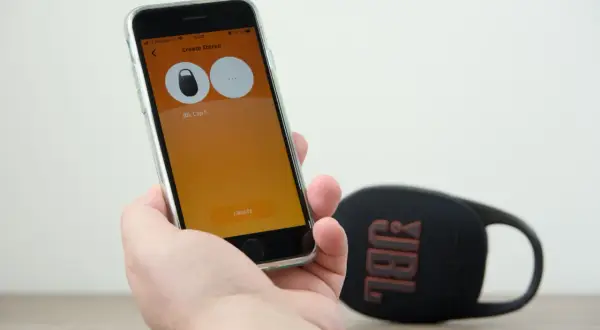 Sprawdzanie, czy słuchawki bezprzewodowe JBL działają z iPhone. Na ekranie telefonu widać aplikację do tworzenia stereo z głośnikiem JBL Clip 5.