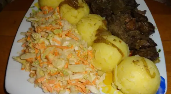 Talerz z wątróbką, ziemniakami i surówką z kapusty i marchewki.