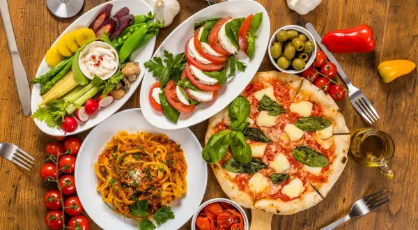 Italienische Pasta Vorspeisen: Tagliatelle Bolognese, Pizza Margherita, Caprese-Salat, Gemüsesticks mit Dip und Oliven. Ein Festmahl!