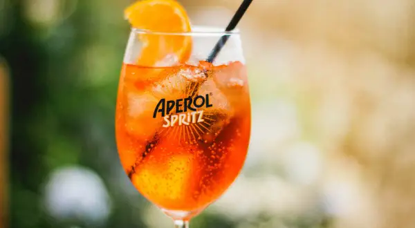 Ett glas med en orange Aperol Spritz, is och en apelsinskiva. Perfekt för en solig dag.