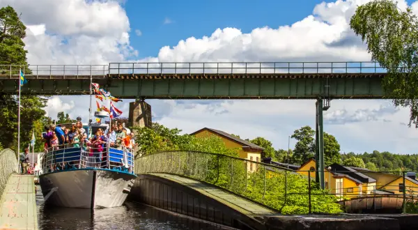 Båt med passagerare passerar under en bro vid akvedukten i Håverud.