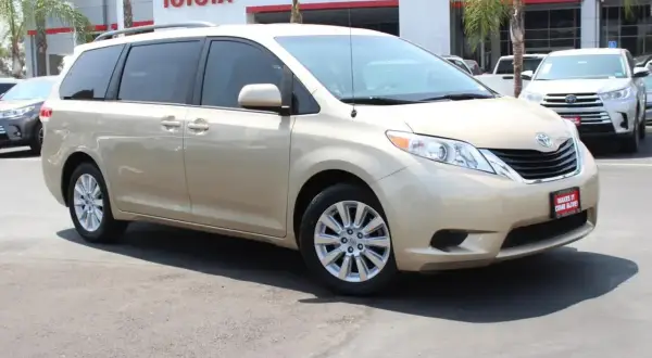 Złoty minivan Toyota Sienna 2025 na tle salonu Toyota.