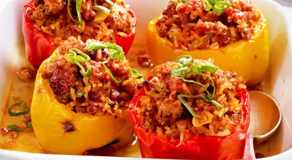 Gefüllte Paprika mit Hackfleisch und Reis, garniert mit Frühlingszwiebeln, in einer Auflaufform.