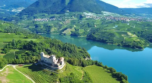 Castello di Thun domina il lago e i vigneti del Val di Non. Un paesaggio incantevole da esplorare, tra storia e natura.