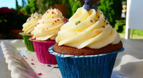 Tre cupcakes med fluffig frosting, dekorerade med strössel och lavendel. Perfekt frosting till cupcakes för en solig dag.