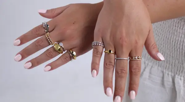 Manos con uñas rosa pálido y anillos de plata y oro. Un anillo dorado tiene un sello, otro un diamante. ¿Qué significa 925 en oro?