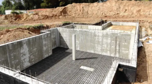 Bau einer Kellerbodenplatte mit Betonwänden und Bewehrung.