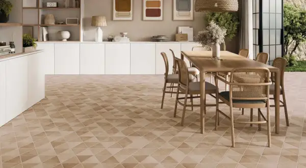 Un salon lumineux avec un carrelage non salissant au motif géométrique discret. Une table en bois et des chaises en rotin complètent l'ensemble.