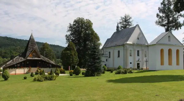 Ustrzyki Dolne atrakcje: drewniana cerkiew i biały kościół na tle zielonych wzgórz.