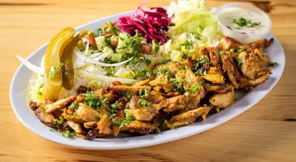 En tallrik med saftig kyckling shawarma, ris, sallad, pickles och en krämig sås. Perfekt för ett snabbt och gott shawarma recept.